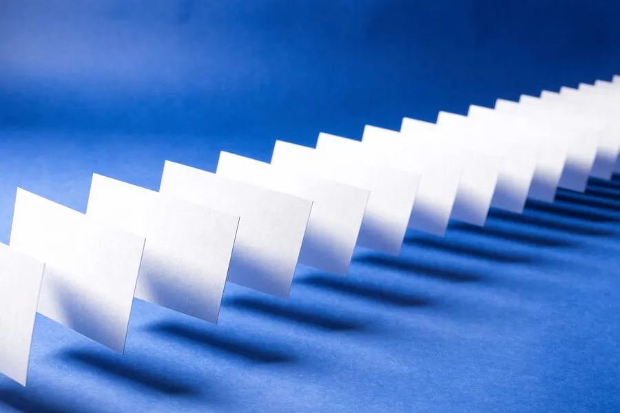 Weiße Karten gleiten in einer diagonalen Reihe über kobaltblaue Fläche