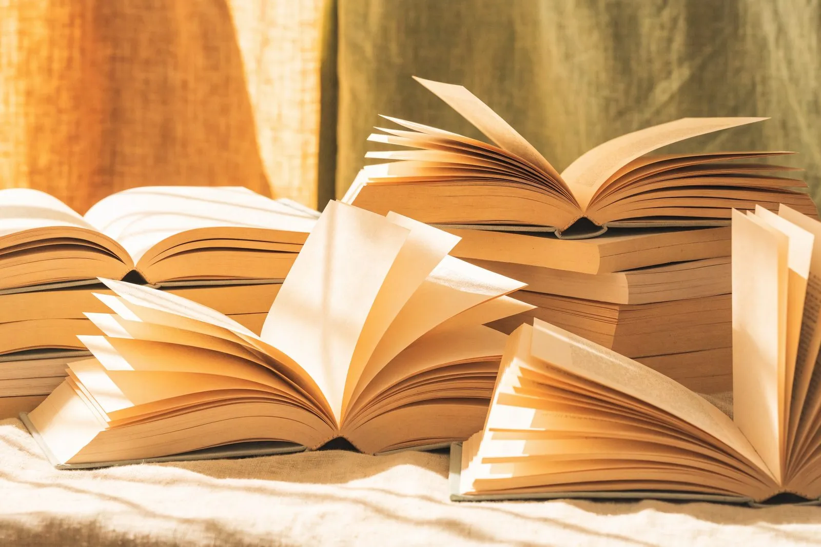 Aufgeschlagene Bücher und Magazine mit leeren Seiten auf cremefarbenem Leinen