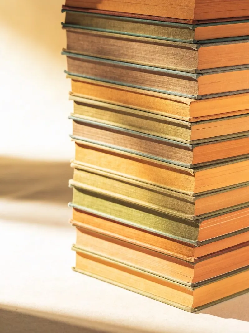 Hoher Stapel Hardcover-Bücher mit Leinenrücken in Oliv und Ocker