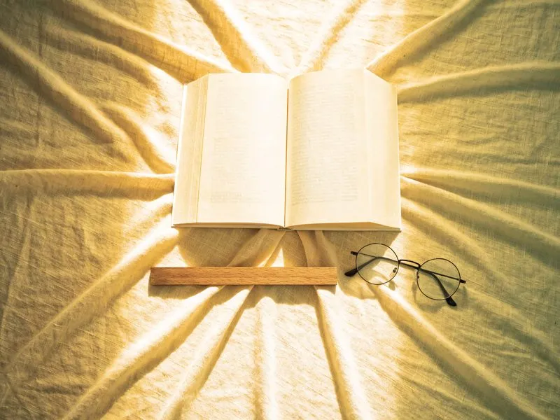 Aufgeschlagenes Buch mit leeren Seiten, Lesebrille und Holzlineal von oben