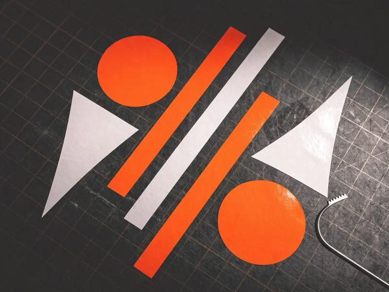 Zugeschnittene geometrische Folienformen in Orange und Weiß auf einer Schneidematte