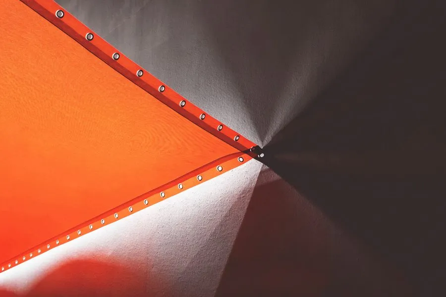 Ecke einer gespannten orangefarbenen Bannerbahn mit Metallösen am Saum